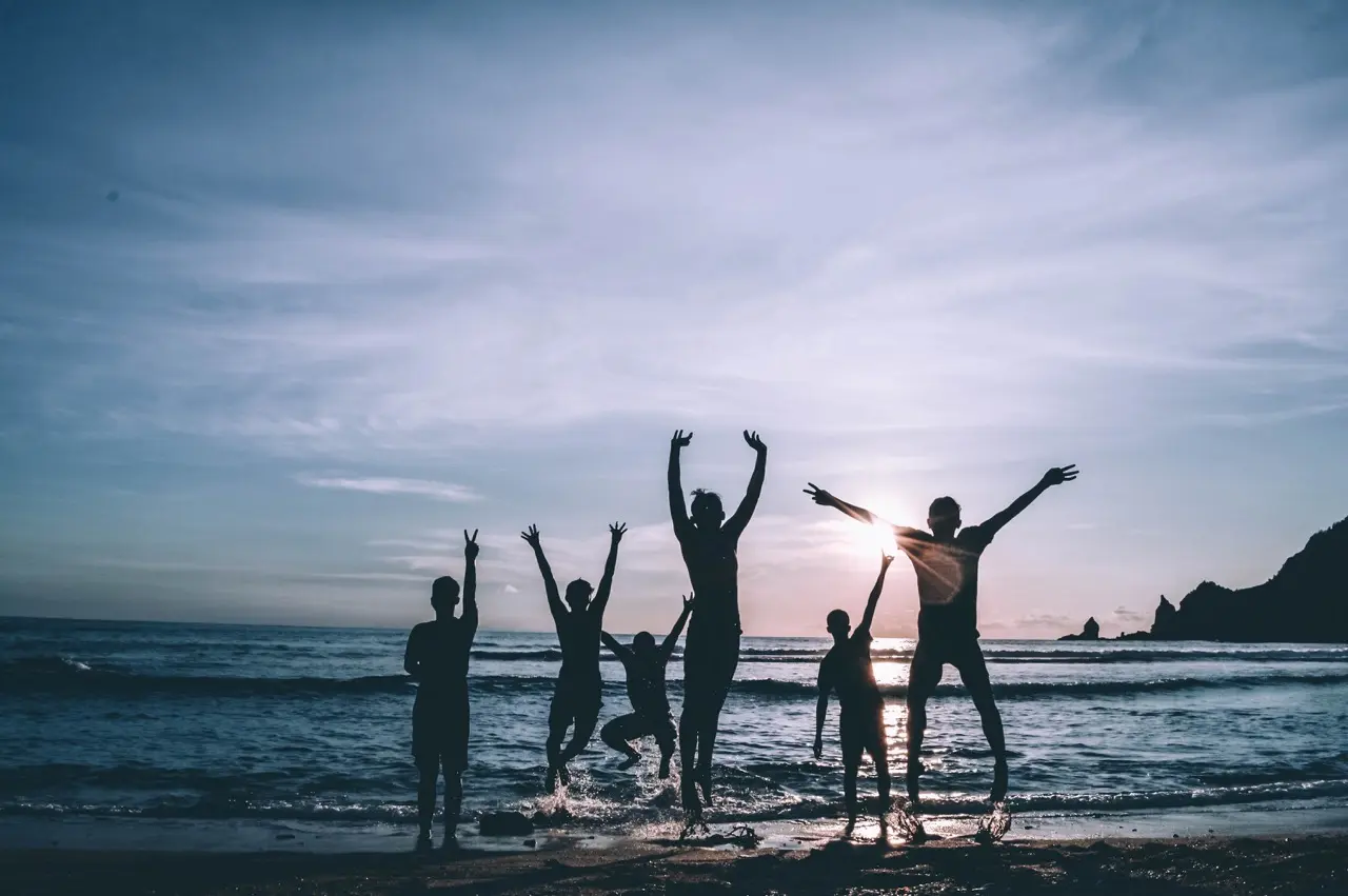 Group of people having fun at the beach at sunset